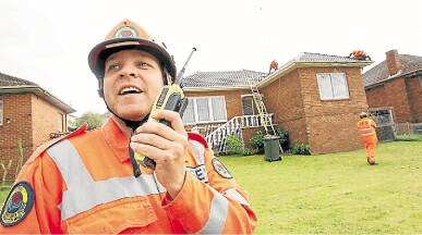 Wollongong SES’s Aaron Spratt  oversees a crew fixing roof tiles on a house in Northcliffe Drive, Warrawong. Picture: DAVE TEASE