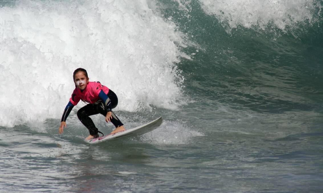 Jada Thomas, 6, rides a wave at Whales Beach during the largest junior surfing competition in Australia. Picture: ROBERT PEET