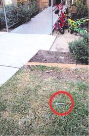 a syringe (circled, right) lies on the patch of grass in the forecourt of the complex. Picture: CHRISTOPHER CHAN