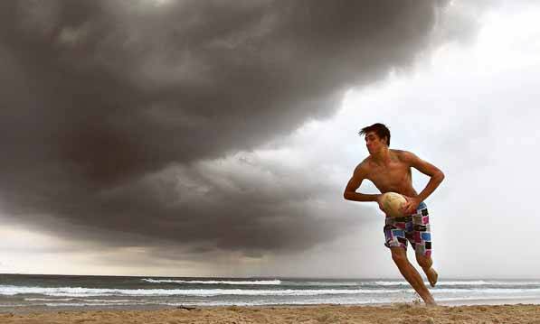 Jayson Taylor plays football on Port Kembla Beach as storm clouds begin to roll in mid-afternoon. Picture: SYLVIA LIBER