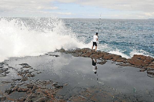 A rock fisherman carries on regardless on a ledge on Hill 60 at Port Kembla yesterday, near where a Yagoona fisherman died yesterday. Pictures: DAVE TEASE
