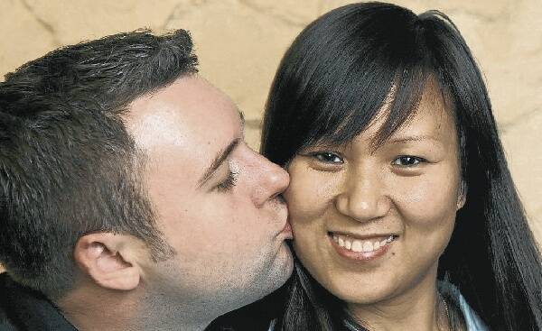 Wollongong's David Batson plants a kiss on his fiancee Wang Peihua. They will marry today, along with a record 91 other couples throughout the state, because of the auspicious date. Picture: ANDY ZAKELI