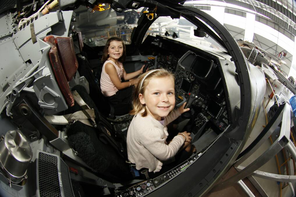 Fascinated: Georgia, rear, and Madison Edwards of Shellharbour, in the cockpit of an F111 that features at Wings Over Illawarra. Picture: DAVE TEASE