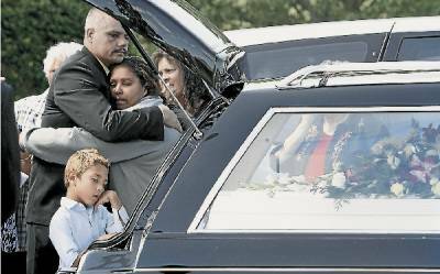 Corey George-Sloan's father Derek comforts family members at Corey's funeral.