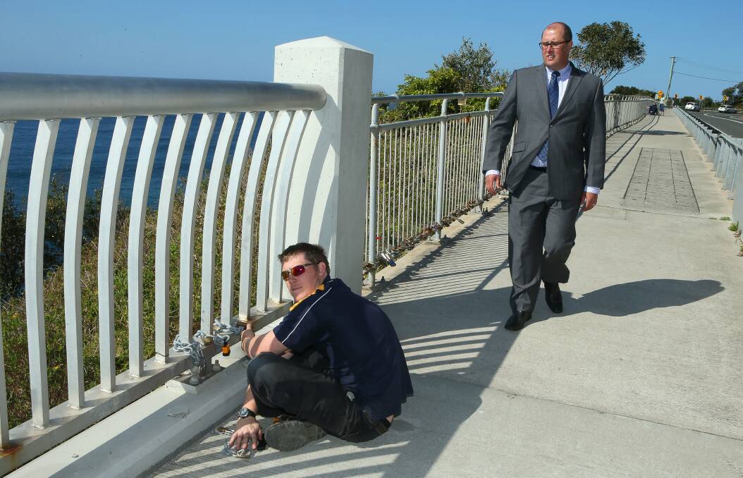 Mercury. News. Unlocked Love. Sean McGee from Macklocks Locksmiths in Warilla is watched by Brad Turner the Regional manager for the roads and Maritime Services as he removes Lovelock padlocks from the rails of the Sea cliff bridge at Clifton. 12th September 2012. Pic. Kirk Gilmour. Story. Glen Humphries