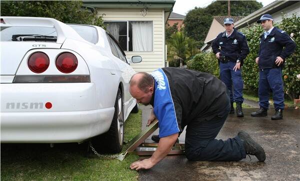 Police officers watch the clamping of a vehicle which was used in street racing and is now on the owner's lawn for the next three months. Picture: KEN ROBERTSON