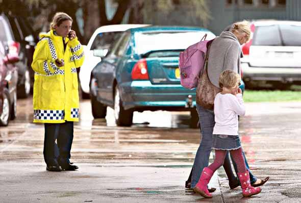 A police officer directs parents collecting their evacuated children at Bulli High School yesterday afternoon.