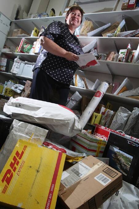 Wollongong Post Office manager Jennifer Walsh is swamped by the volume of parcels generated by online shopping. Australia Post has extended opening hours and employed extra staff. Photo: KEN ROBERTSON