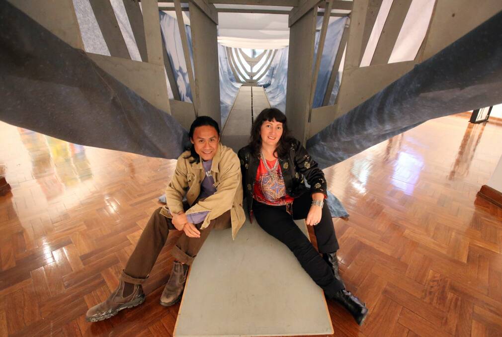 Artist Dacchi Dang and Me, The Road and I curator Virginia Settre in the recreation Dang made of the refugee boat he came to Australia in. Picture: ROBERT PEET