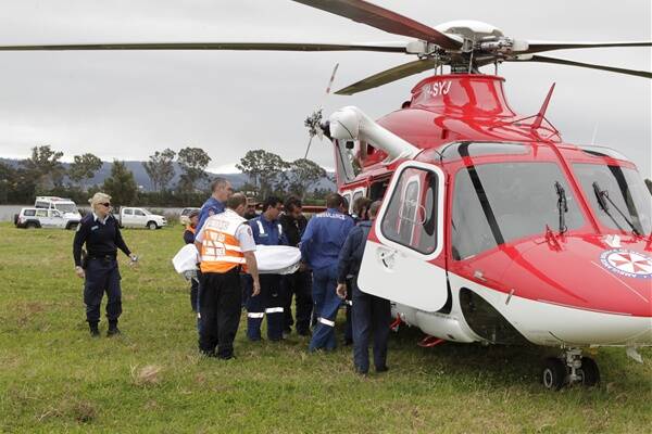 NSW Ambulance Operations Commander, Ambulance officers and paramedics from the air ambulance load the injured man into the waiting helicopter for transportation to the Royal North Shore spinal care unit. Photo: CHRIS DOBIE