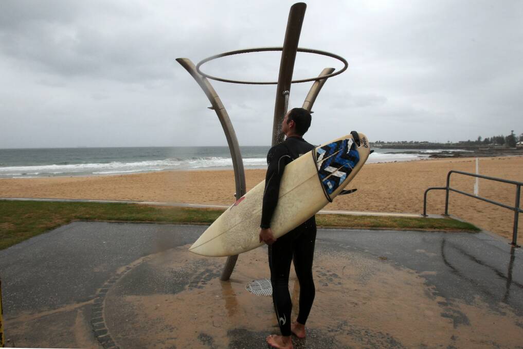 A lone surfer rinses off after rain and lower temperatures kept the beaches closed and empty on Christmas Day. Picture: GREG TOTMAN