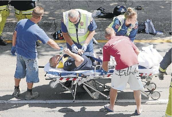 Looked after: An injured motorcyclist is treated at the scene. Picture: DAVID TEASE