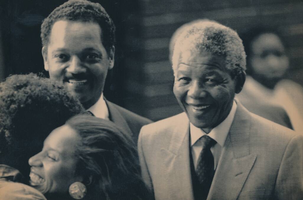 Nelson Mandela and former US Presidential Candidate, Jesse Jackson, look on as their wives, Jacqueline Jackson and Winnie Mandela embrace (1990).