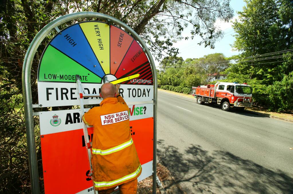 Mount Kembla Rural Fire Service deputy captain Ben Jacobsen moves the fire danger sign on Cordeaux Road, Mount Kembla to catastrophic in in January. Picture KIRK GILMOUR
