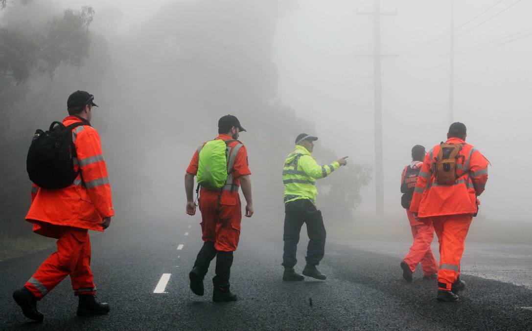 Police and SES personnel walk along the road between Panorama House and the Cliff Hanger Cafe at Bulli Tops during their search. Picture: KIRK GILMOUR