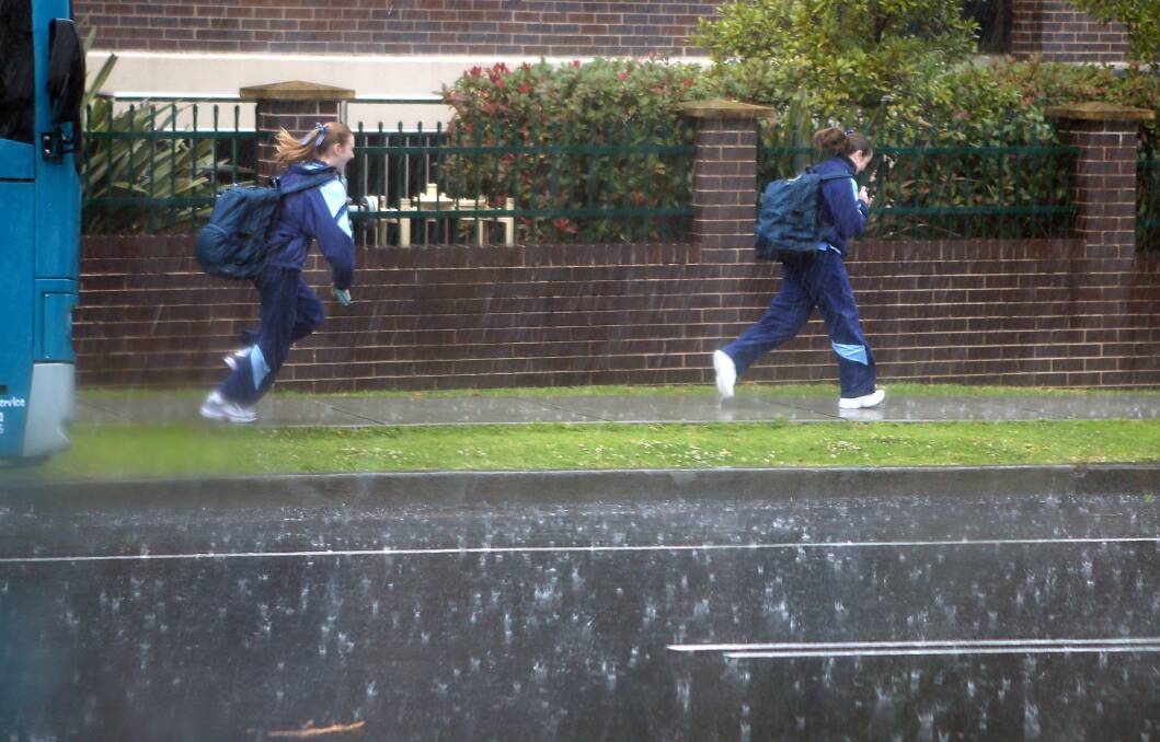 Students spring for shelter during heavy rain in Wollongong. Picture: KIRK GILMOUR