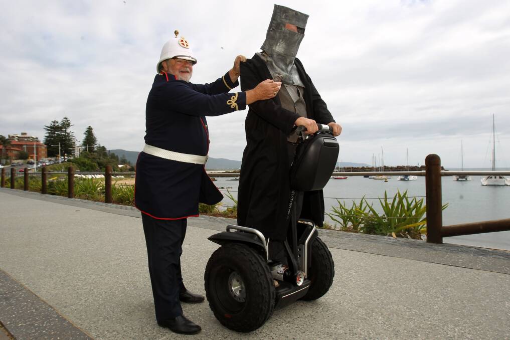 British soldier Brian Ash offers Jeremy Lawson (Ned Kelly on a Segway) a lamington at yesterday's launch. Picture: GREG TOTMAN