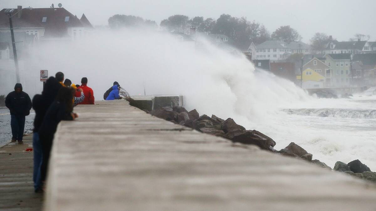 People watch the waves crash into the coast at Winthorp, Massachusetts. Picture: GETTY IMAGES