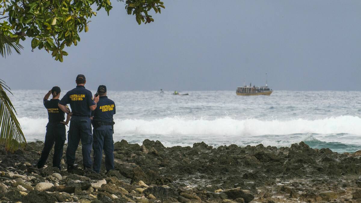 Customs officials watch as a boat carrying asylum seekers comes ashore on Cocos Island last year. Picture: KAREN WILLSHAW 
