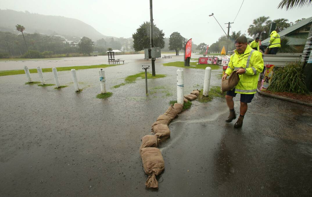 Wollongong City Council staff place sandbags in front of the Beach Kiosk at Stanwell Park on Friday. 