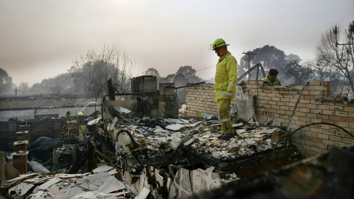 A firefighter inspect a home destroyed by fire during Canberra's 2003 bushfires. Picture: SEAN DAVEY