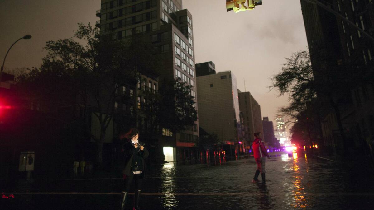 People take photos on a flooded street in New York City. Picture: REUTERS