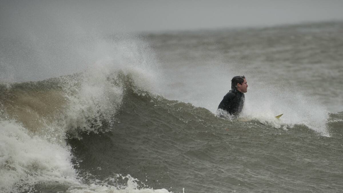 A surfer braves the waves in Coney Island. Picture: REUTERS.
