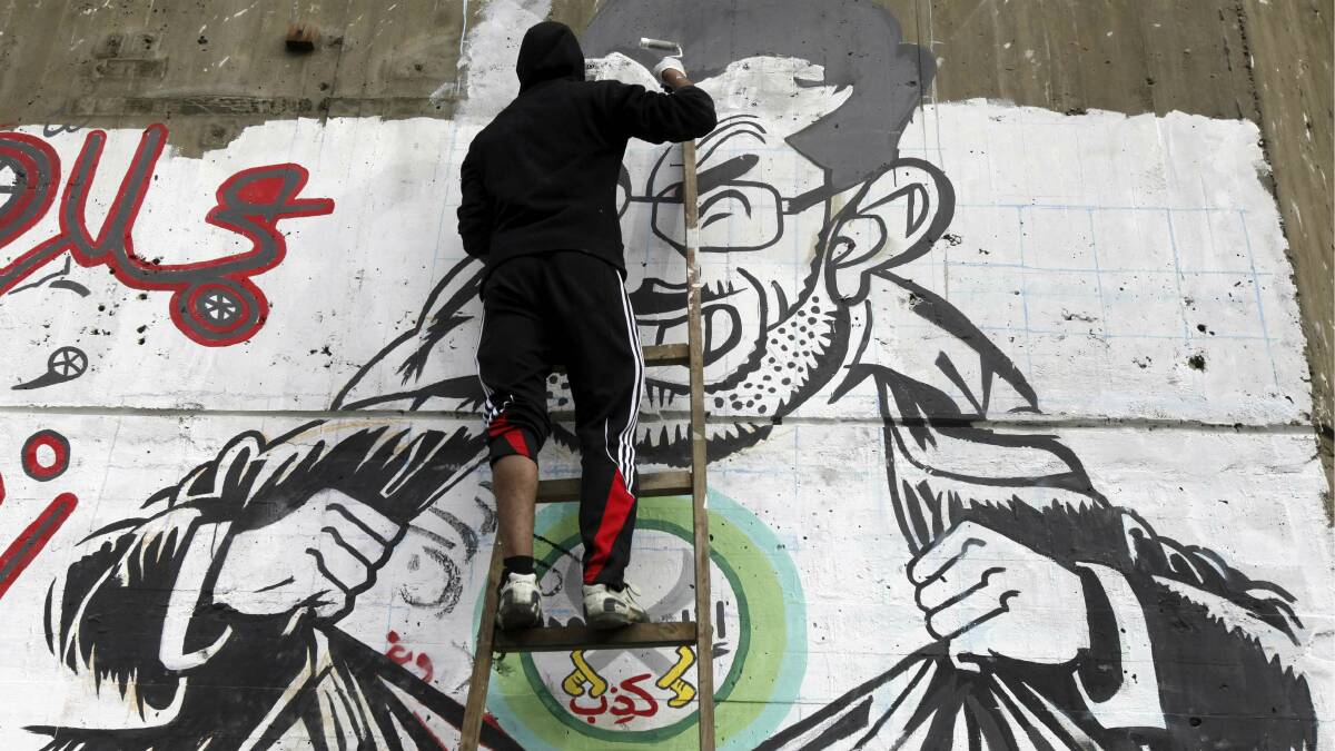 A man in Egypt paints graffiti representing President  Mohamed Mursi. Picture: REUTERS