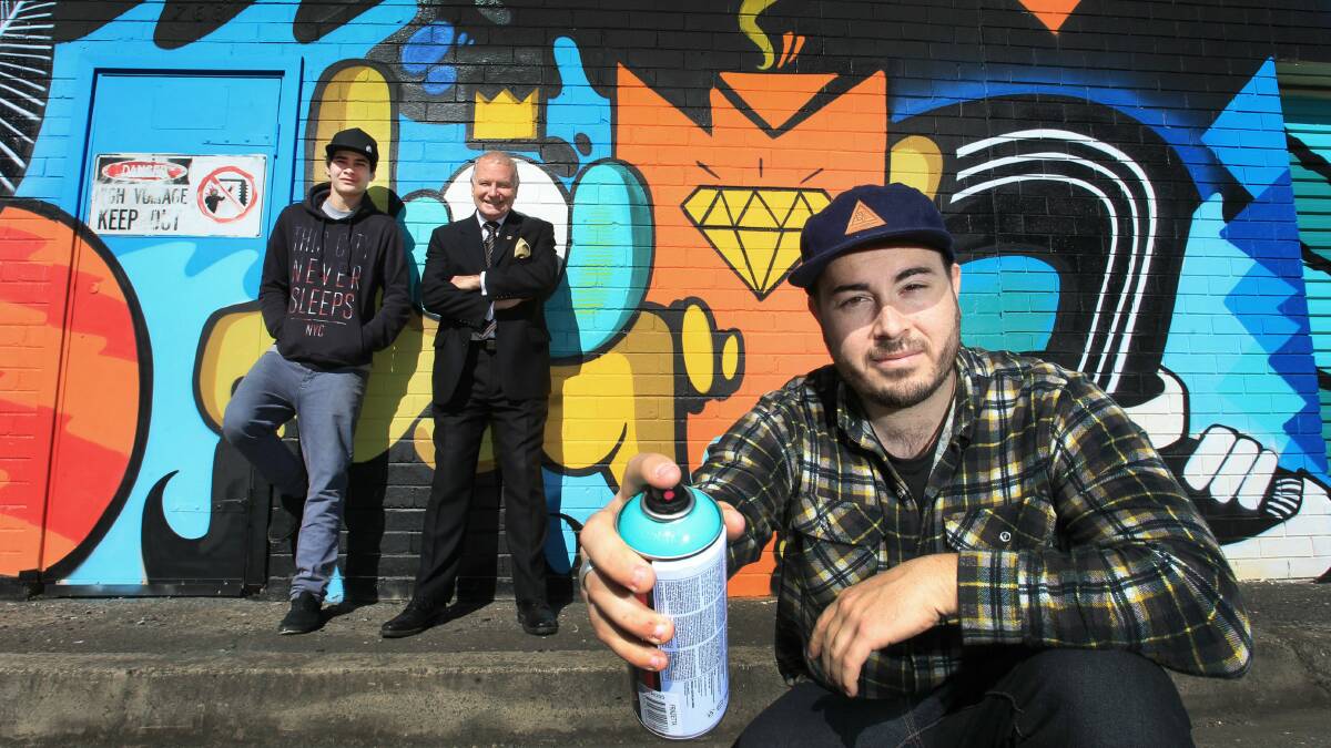 Artists Simon Grant (front) and Liam Forrester with Lord Mayor Gordon Bradbery, and their spectacular mural. Picture: ORLANDO CHIODO