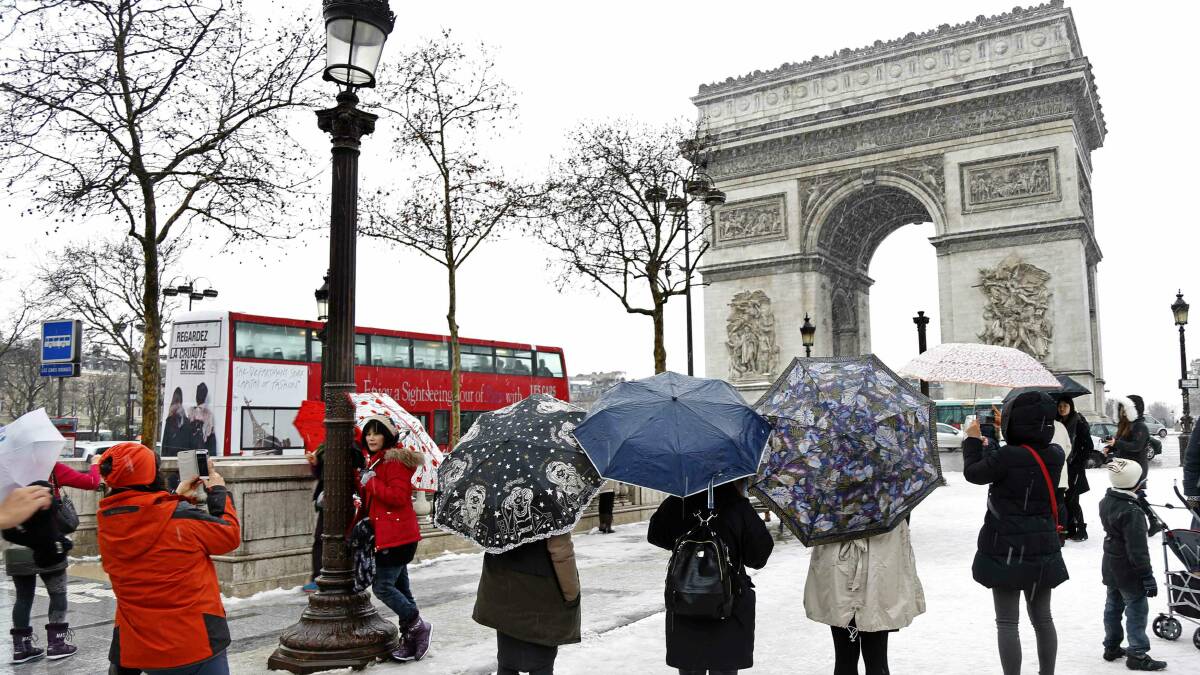 Tourists take photos of the Arc de Triomphe in Paris. Picture: REUTERS