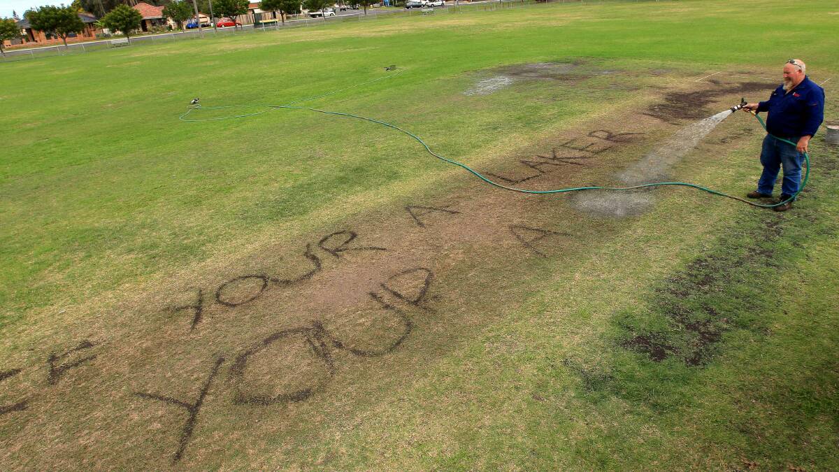 Lake Illawarra Cricket Club president Billy Clark cleaning the vandalised wicket. Picture: SYLVIA LIBER 