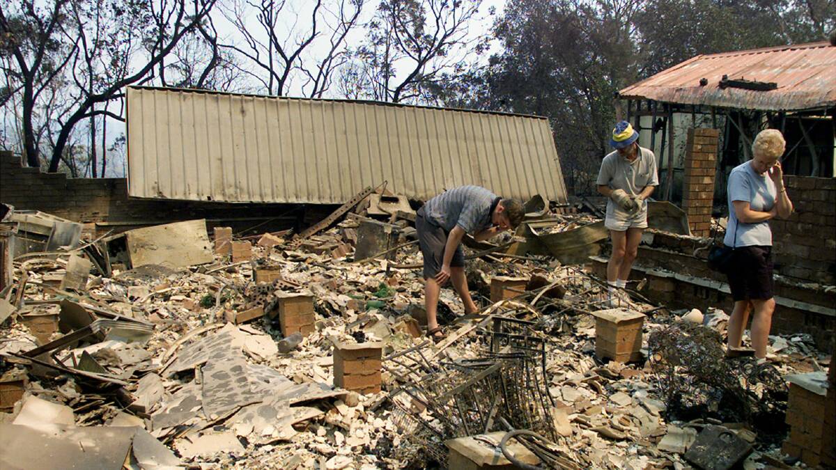 Owners of a destroyed home in the Blue Mountains sift through the wreckage. Picture: REUTERS