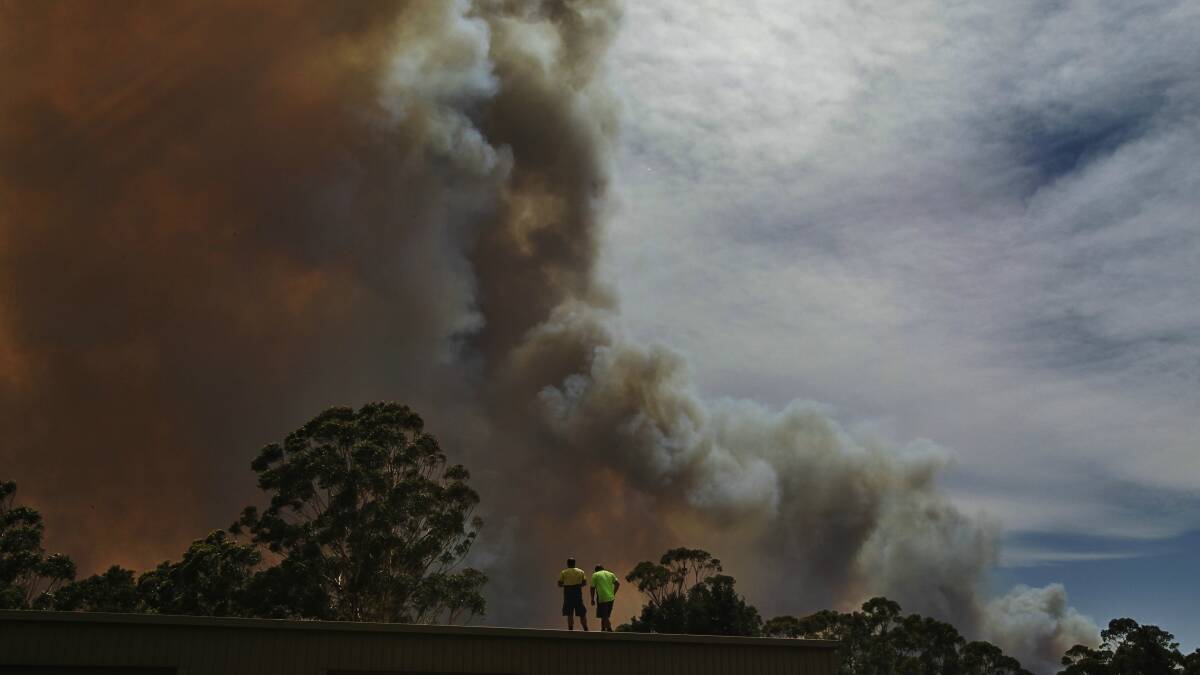 Two men watch the fire burn at Wandandian on Tuesday. Picture: NICK MOIR