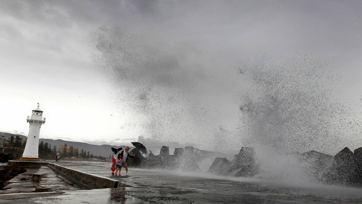 Sydney visitors Bluebell, Jasmine, Mark and Candy Hong are saturated  by huge surf at Wollongong Harbour yesterday. Picture: SYLVIA LIBER
