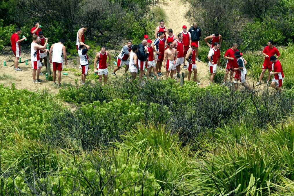 Dragons players make their way around the East Corrimal sand dunes during training.