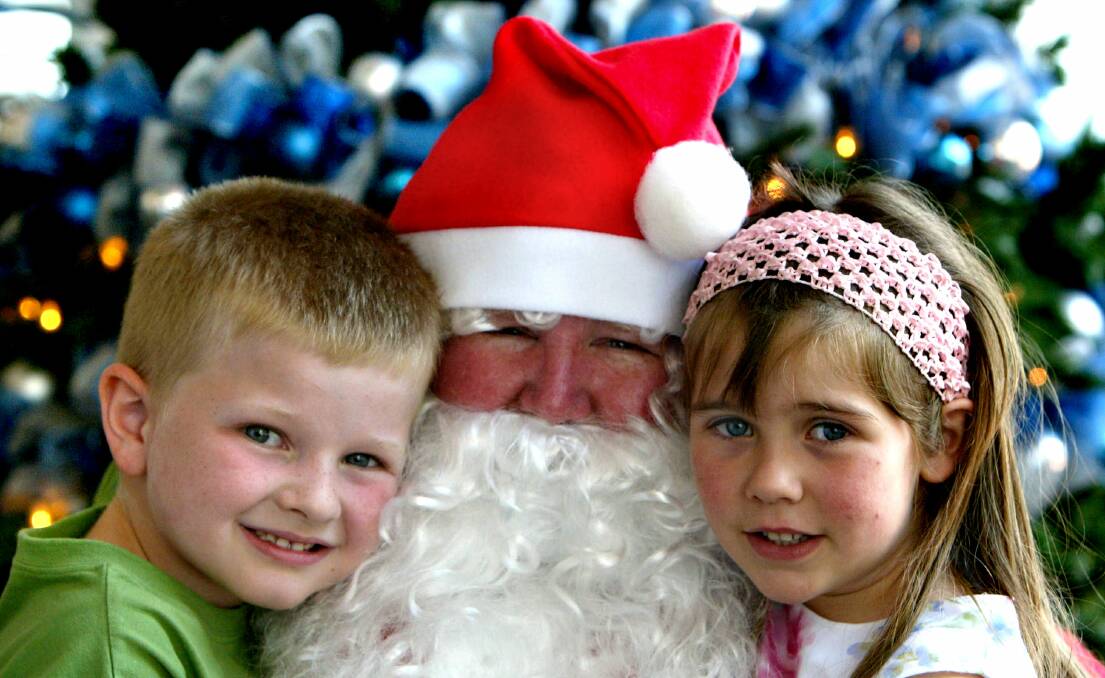 Five-year-olds Thomas and Beatrice give Santa a hug at Wollongong City Library.