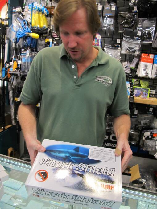 Dennis O'Donnell shows the Shark Shield shark deterrent device at his Maui store.  