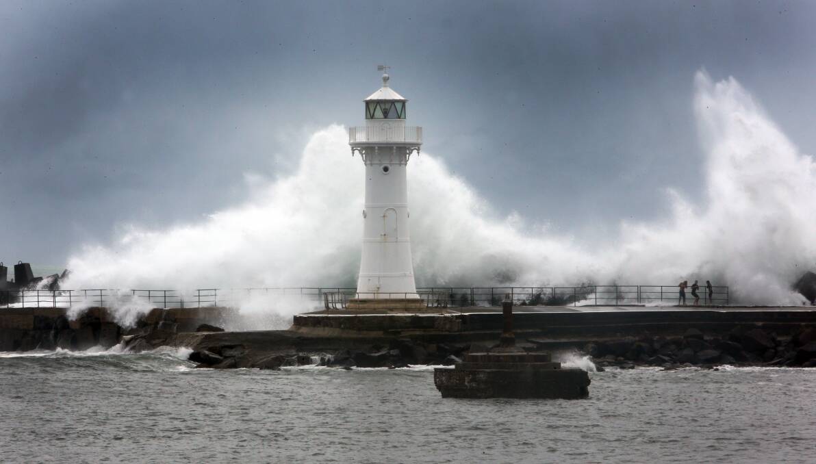 The Wollongong Breakwater Lighthouse stands in the path of a huge wave on January 29. Picture: ROBERT PEET