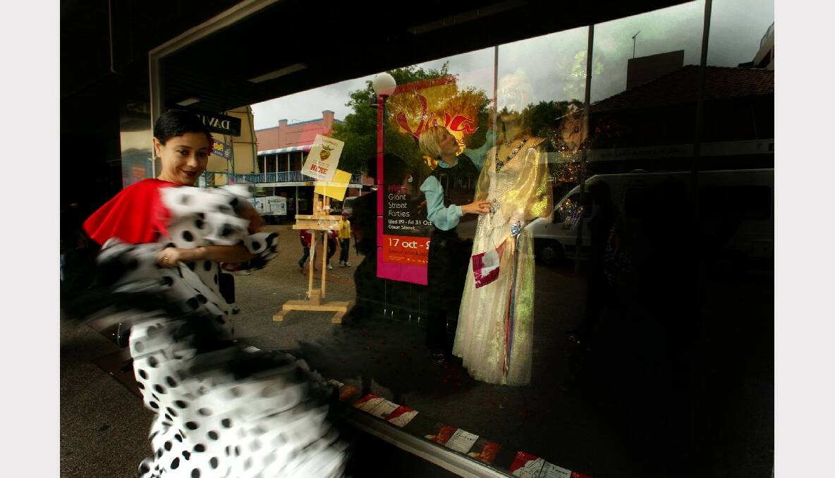 Elizabeth Espinosa performs a Spanish dance as Tania Daniels decorates one of the David Jones windows in Crown St Mall.