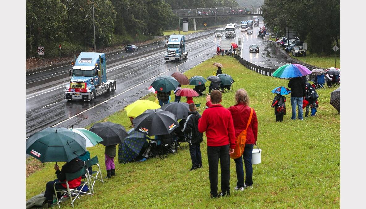 Rain-soaked spectators along Mt Ousley Road for the 2013 i98FM Camp Quality Convoy for Kids. Picture: ADAM McLEAN