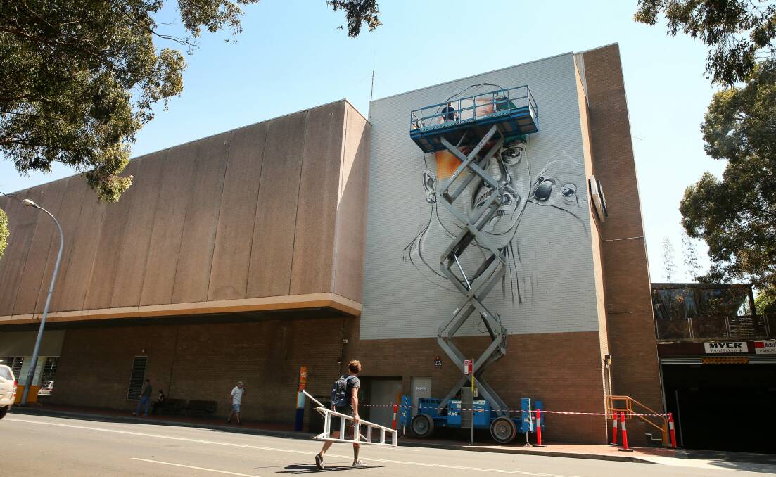 The artist known as Smug gets busy creating his wonderwall on the Wollongong Myer building. Picture: KIRK GILMOUR