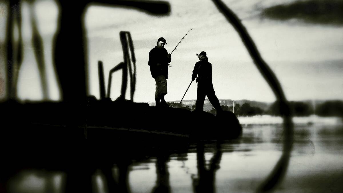 These two fishermen caught the best of the weather and a few bites from the fish yesterday on Lake Illawarra. Picture: DAVE TEASE