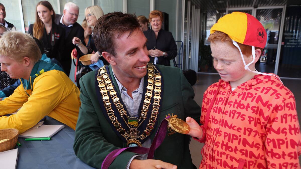 Warilla Olympian David Smith shows his gold medal to Jett Murray, 8, at Shellharbour Civic Plaza on Sunday. Picture: ADAM McLEAN