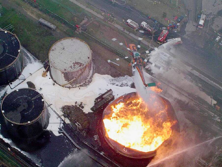 An enormous explosion sends a fireball 30m in the air over Port Kembla and tears apart a steel tank containing ethanol.