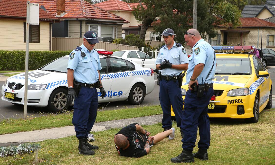 Police stand guard over a man arrested in Fairy Meadow on January 9. Picture: KIRK GILMOUR