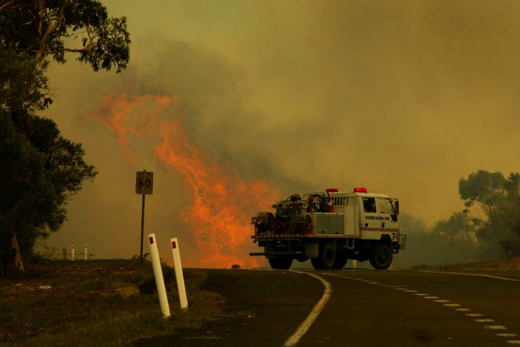 Fire jumps the road near HMAS Creswell at Jervis Bay, forcing a bushfire crew to turn and retreat.