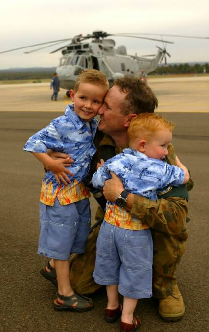 Lieutenant Nathan Lewis with his sons, Callum, 4, and Noah, 2, after the Sea King helicopter he piloted in the Solomon Islands touched down at HMAS Albatross in Nowra.