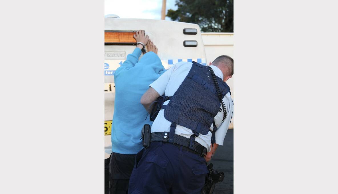 An officer from Strike Force Riordan arrests one of six people.