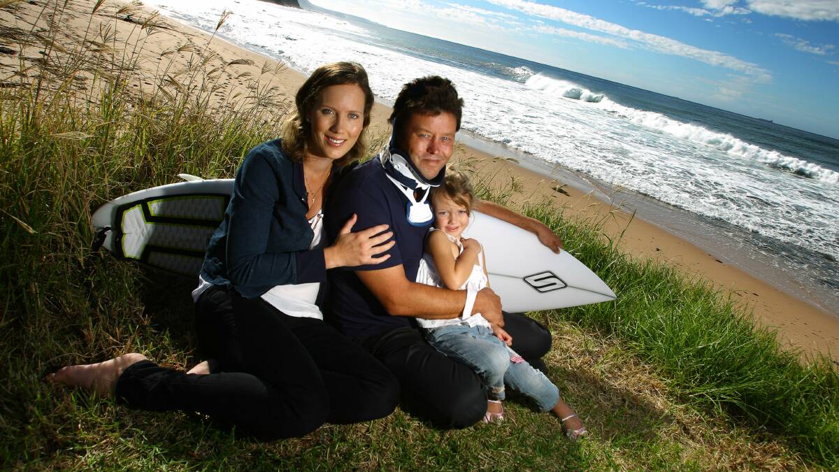 Injured surfer Mike Haines at Wombarra Beach with his wife Jade and daughter Lillie, 4. Picture: KEN ROBERTSON