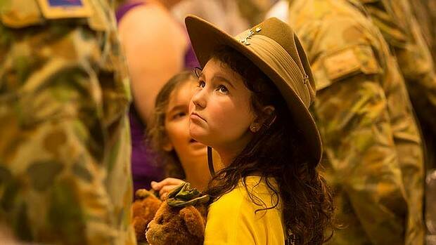 Wearing her father Blake Dobe's slouch hat, Madison, 8, looks up at him while Prime Minister Tony Abbott makes his speech. Picture: GLENN CAMPBELL